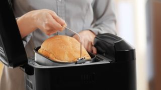 A loaf of bread being removed from a bread machine