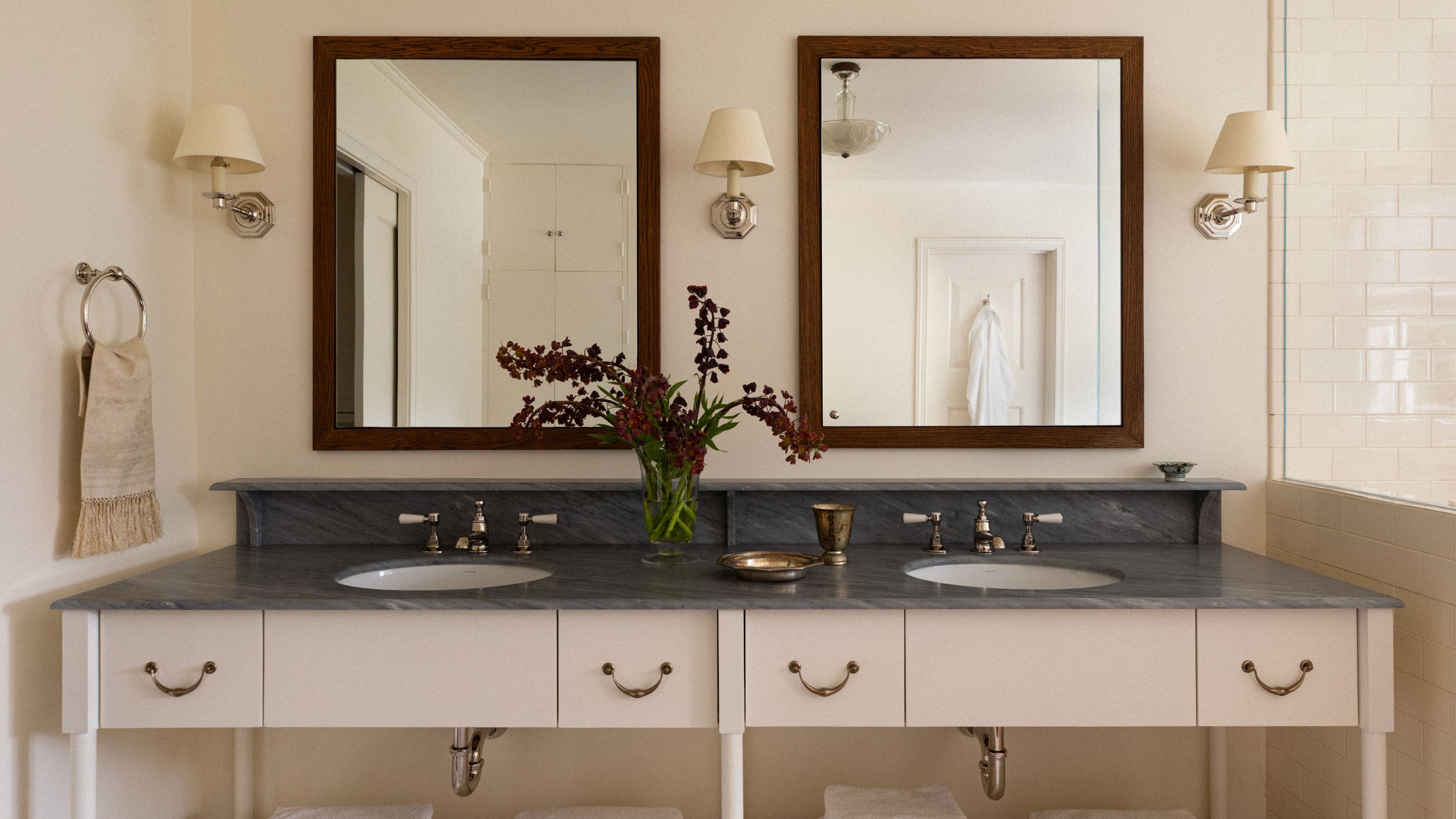 a neutral bathroom with a large his and hers vanity with double mirrors and a blue gray marble top