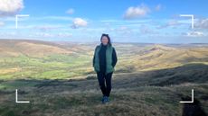 Susan Griffin, writer and hiking enthusiast, on a hike with beautiful background of rolling green hills and blue sky after learning about the top hiking mistakes to avoid