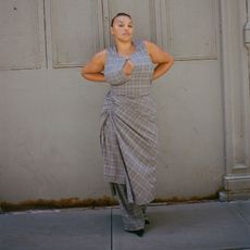 a model poses against a gray backdrop wearing a gray plaid dress with a keyhole cutout