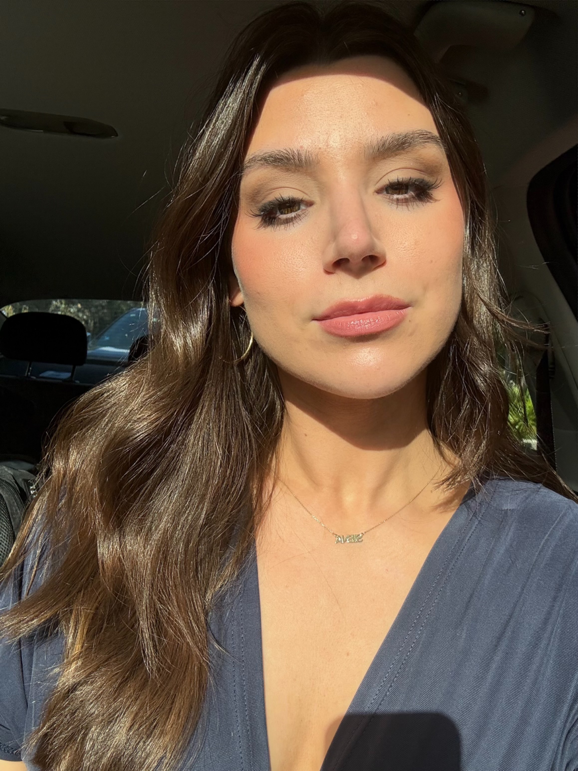 Siena Gagliano wearing a blue shirt with long brown curled hair after using FORTA setting spray