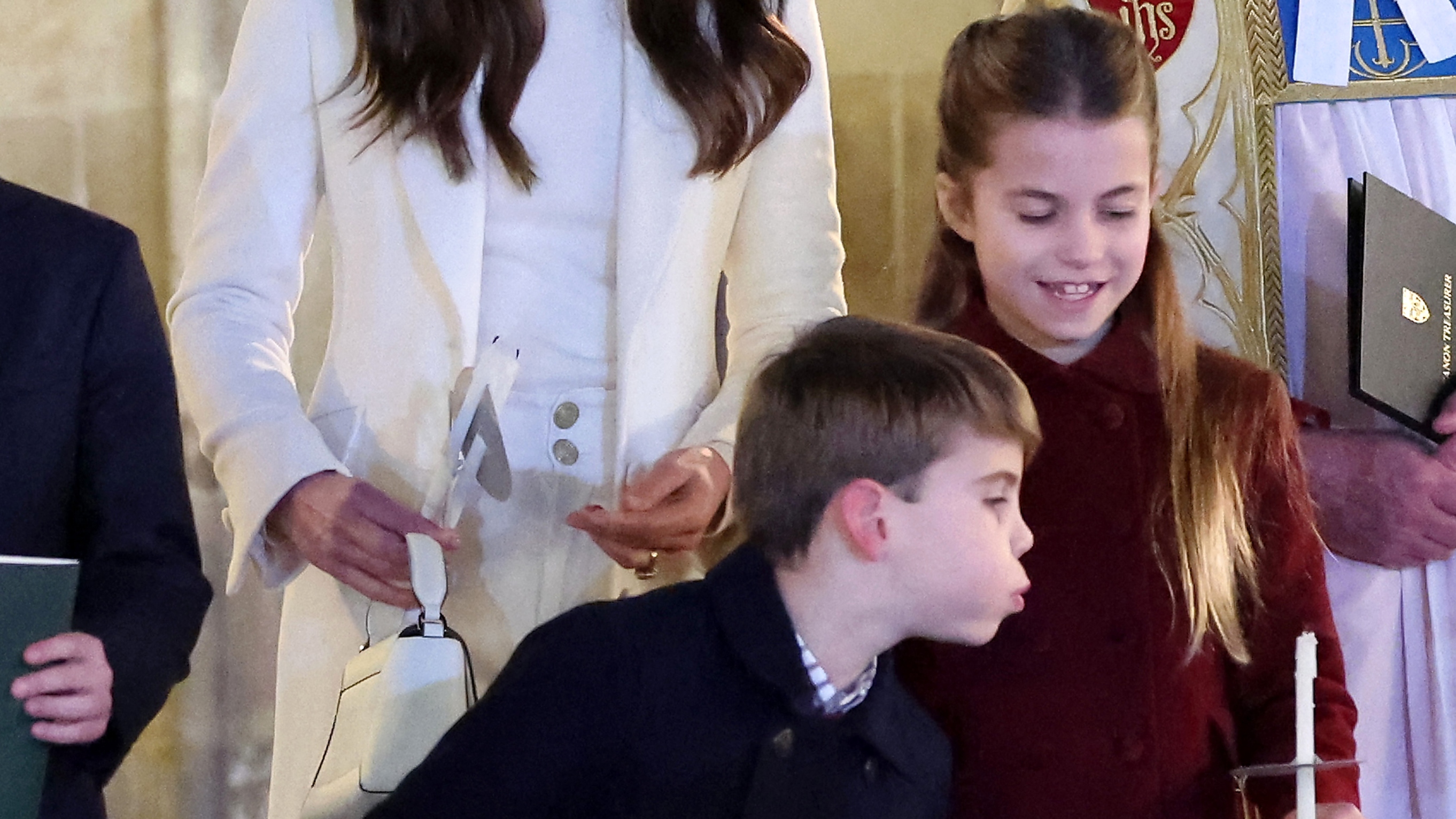 Princess Charlotte of Wales has her candle blown out by Prince Louis of Wales at the "Together At Christmas" Carol Service" at Westminster Abbey in London on December 8, 2023