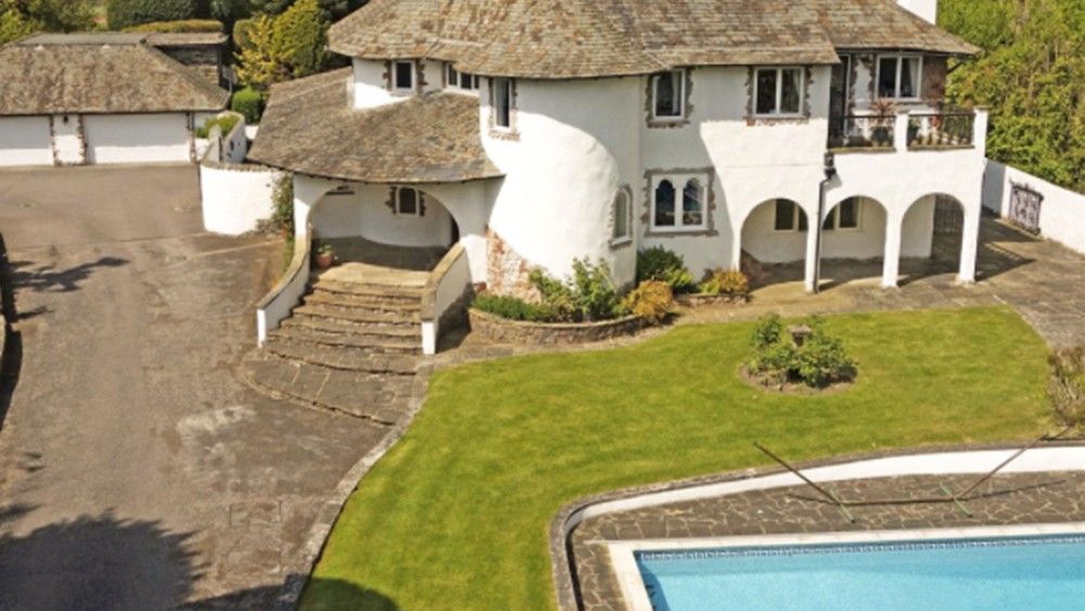 white villa with brown roof green lawn swimming pool and roadway