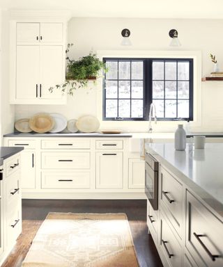 white kitchen with hardwood floor, rug, kitchen island, all white with black countertops, white marble on kitchen i