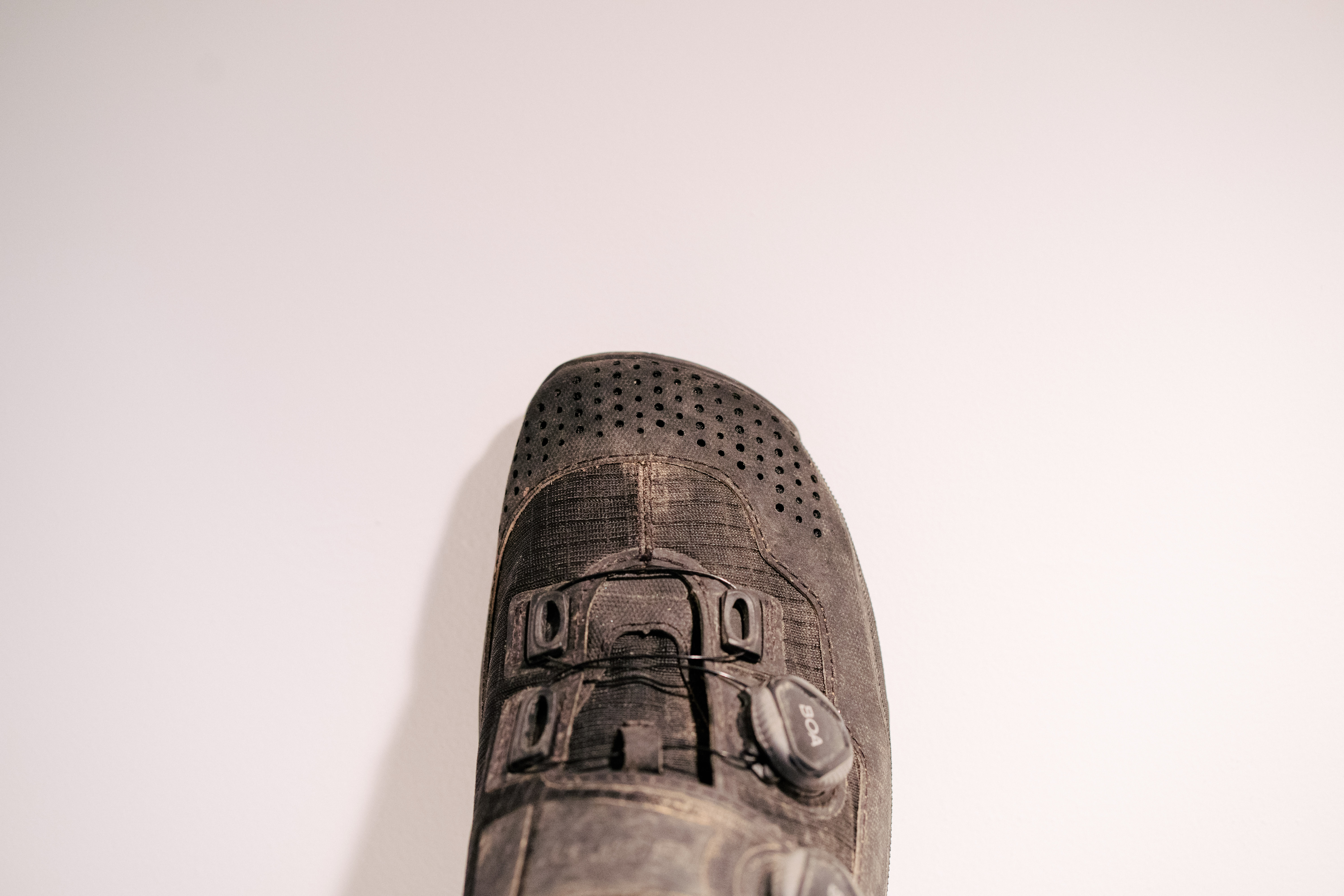 A black, muddy gravel shoe on a white shelf