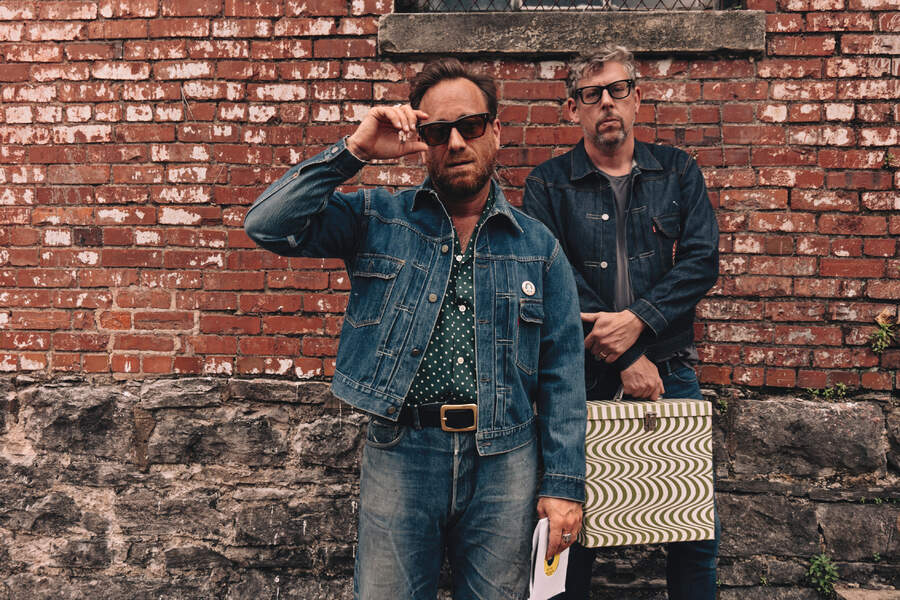 The Black Keys standing in front of a brick wall