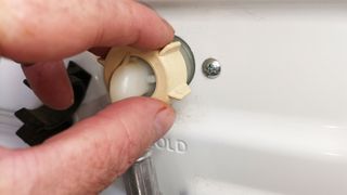 Hand unscrewing cold water washing machine pipe