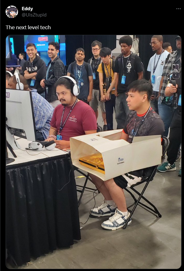 An EVO 2023 attendee using a box to cover their fightstick during a match.