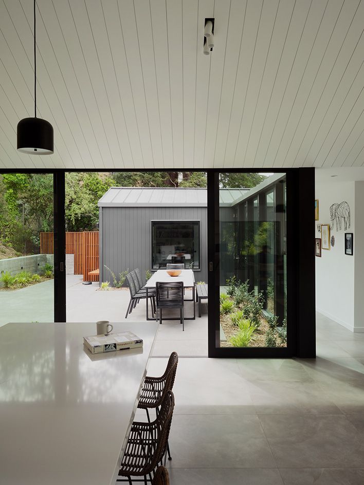 inside looking towards the paved courtyard thrugh large glazing at Mill Valley house Courtyard house