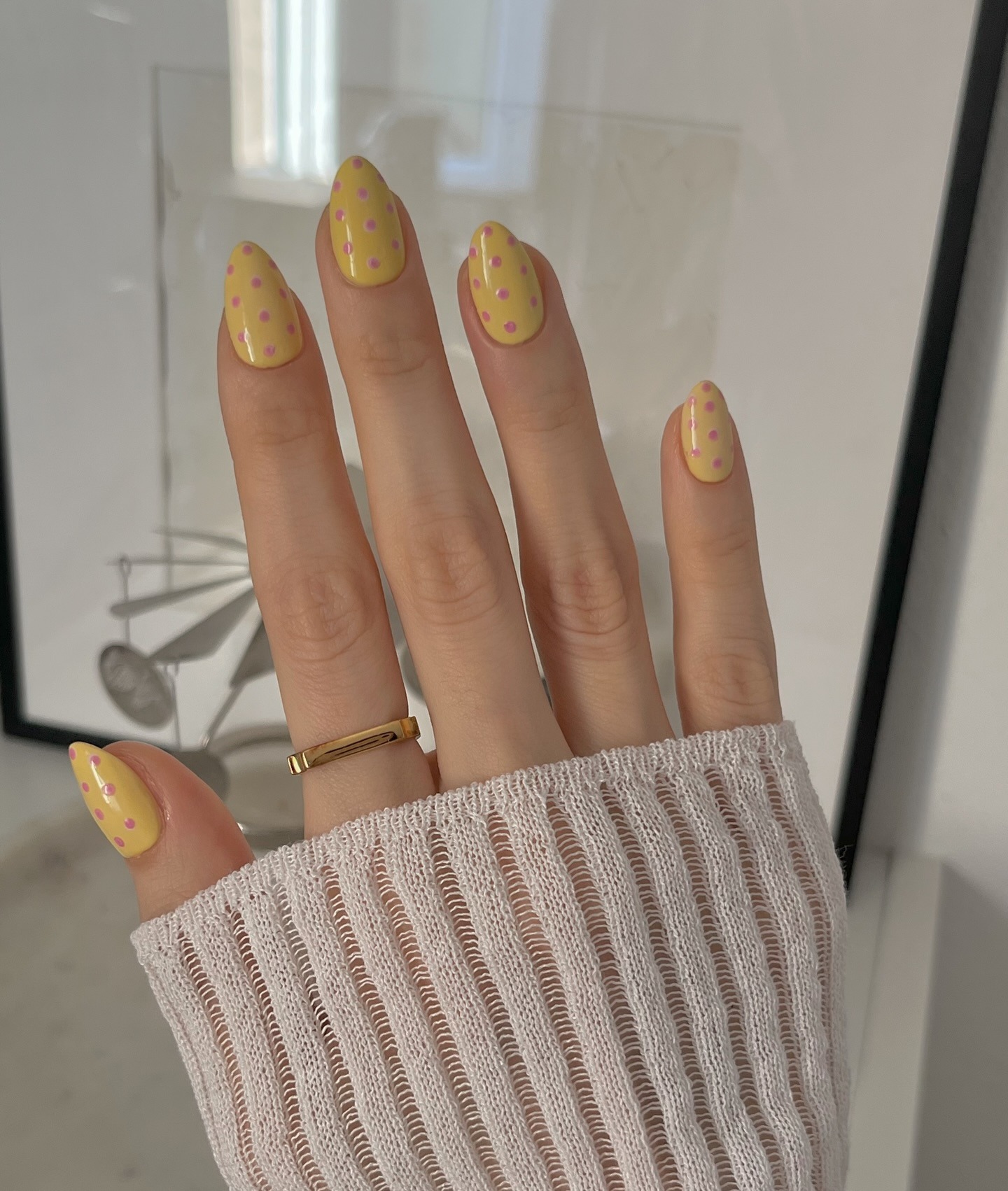 A pastel yellow manicure with pink polka dots