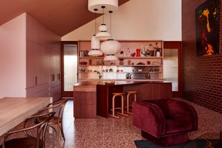 Pink kitchen with dark red-toned wood island in triangle shape