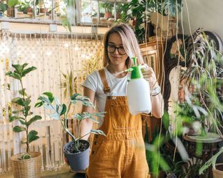 young woman misting houseplant