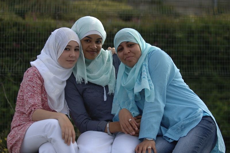 Three happy Muslim women sitting together.