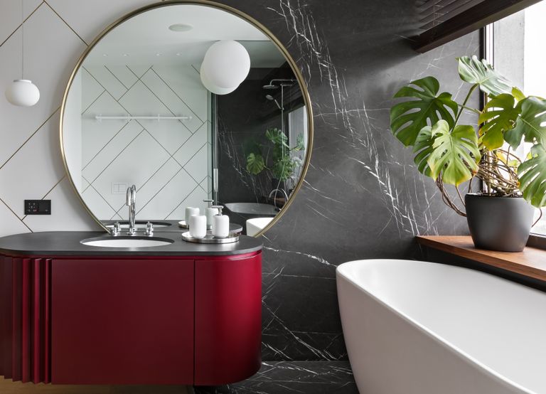 A small bathroom with a red vanity and a small bathtub