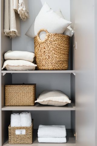 A minimal clutter-free laundry closet with laundry baskets and storage baskets on tidy shelves