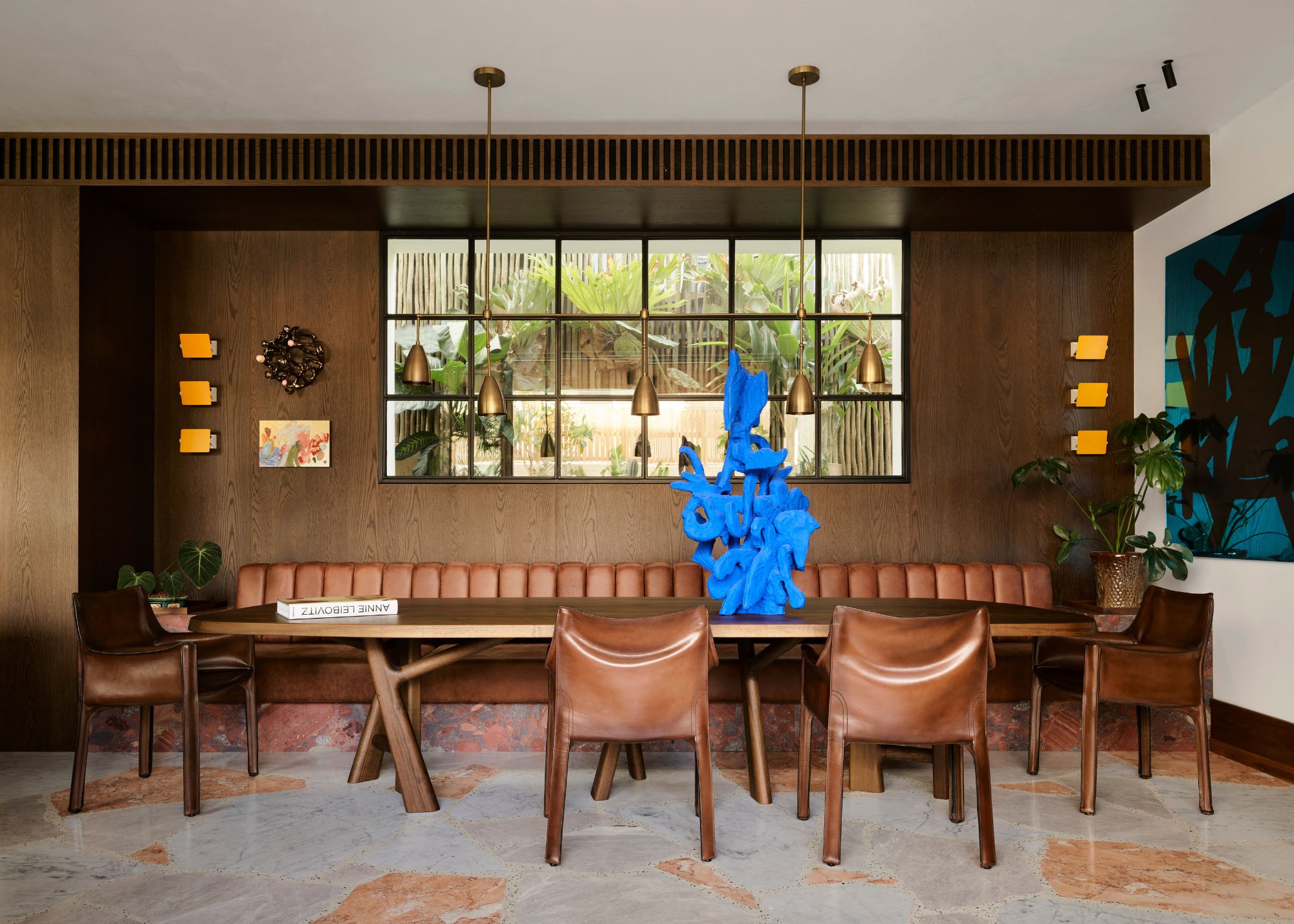 A dining room with leather chair and sofa, brown wals and Palladiana flooring