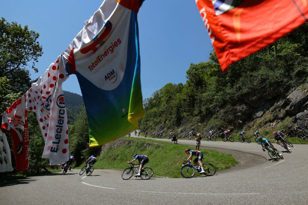 The pack of riders (peloton) cycles during the 15th stage of the 111th edition of the Tour de France cycling race, 197,7 km between Loudenvielle and Plateau de Beille, in the Pyrenees mountains, southwestern France, on July 14, 2024. (Photo by Thomas SAMSON / AFP)