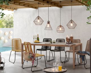 Caged pendants in mixed shapes hanging over alfresco dining table, with mix and match chairs.