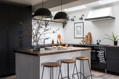 Monochrome kitchen with wooden floors, wooden worktops and a breakfast bar island
