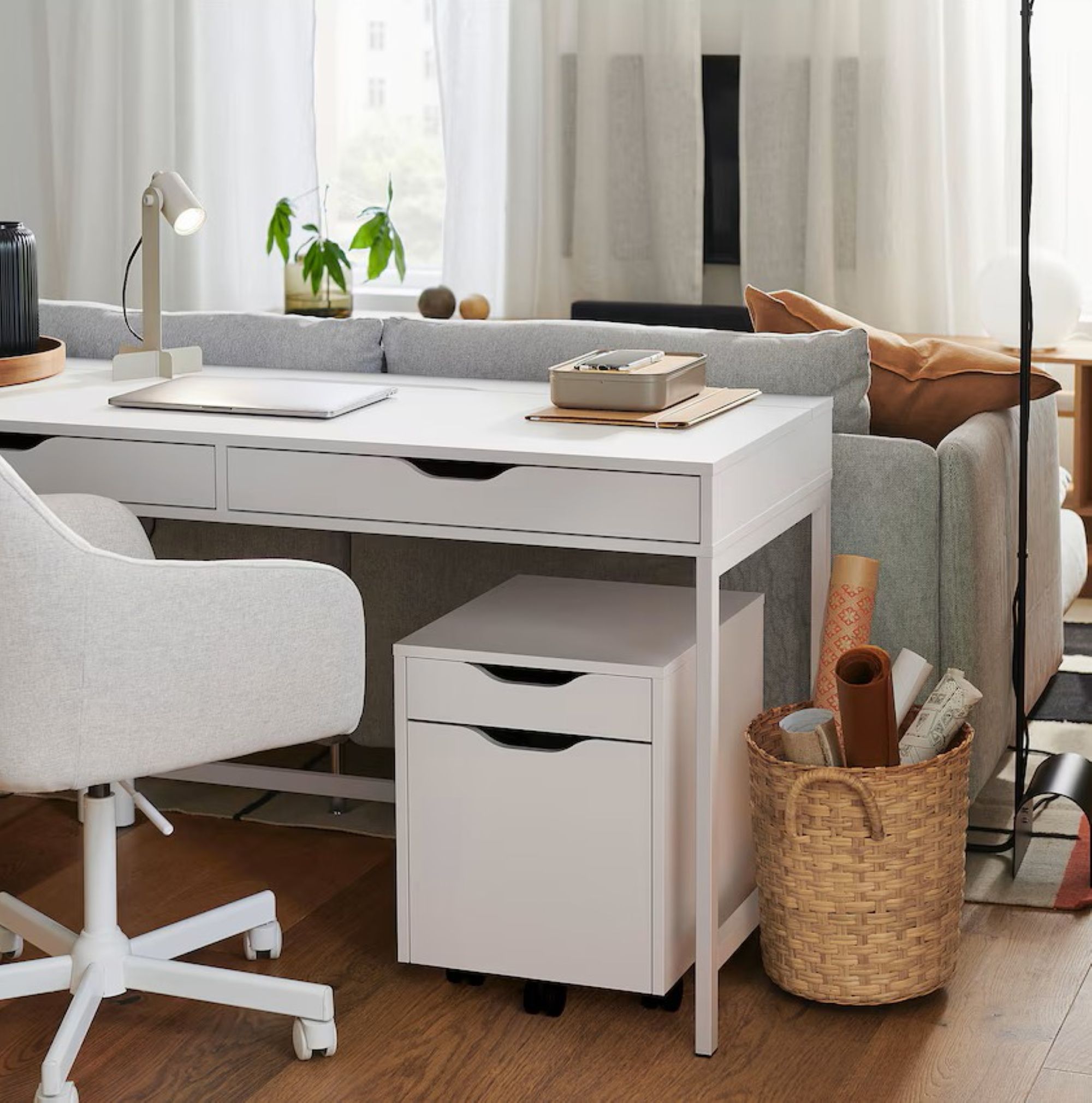 room with a white desk in front of a grey couch