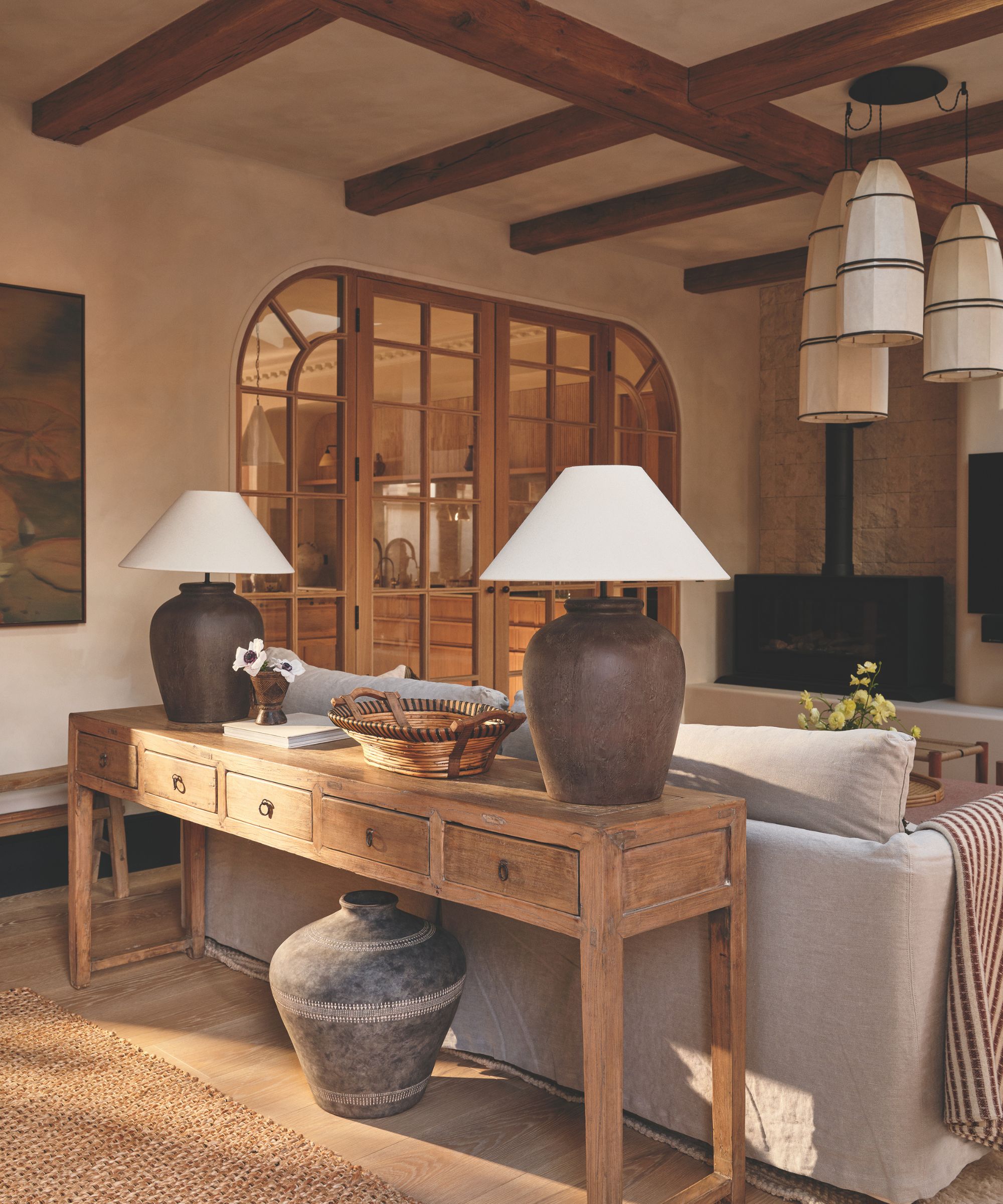 rustic living room with textured plaster walls, a gray couch and a wooden console table behind