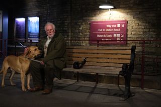 PHIL DAVIES as Edward sitting on a bench with his dog in Platform 7