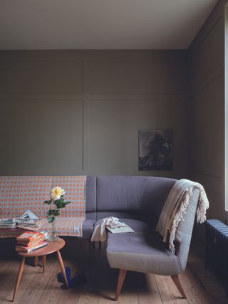 A living room with light gray walls and a curved lavender colored sofa