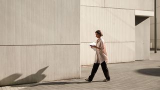 Woman walking between buildings for a break looking at phone in the sunshine