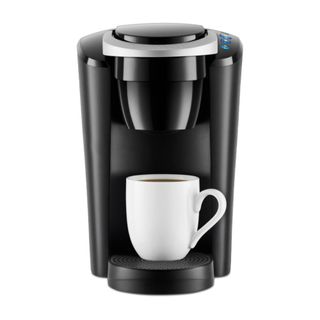 A silver and black Keurig K-Compact Single-Serve K-Cup Pod Coffee Maker with a white coffee cup on it