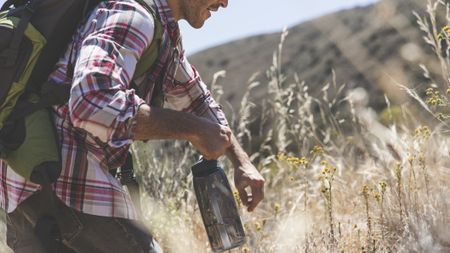 Man hiking outdoors with a water bottle in his hand