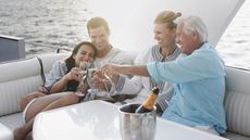 Two couples celebrate with champagne on a yacht.