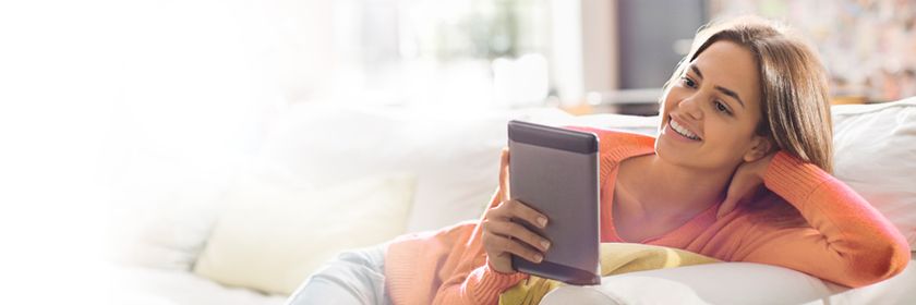 A woman smiles as she uses a tablet