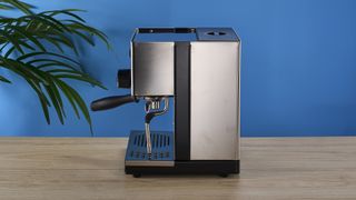 Rancilio Silvia in Stainless steel on a wooden worktop with a blue wall in the background.