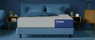 The image shows the Casper One mattress on a blue bed foundation in a blue bedroom