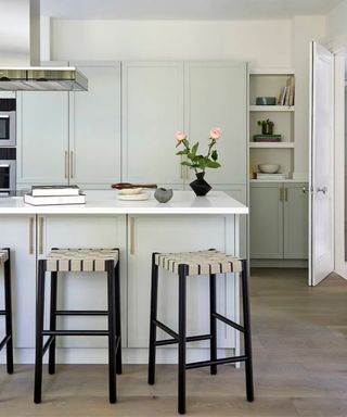 Kitchen with pale gray cabinets and and island with white countertops