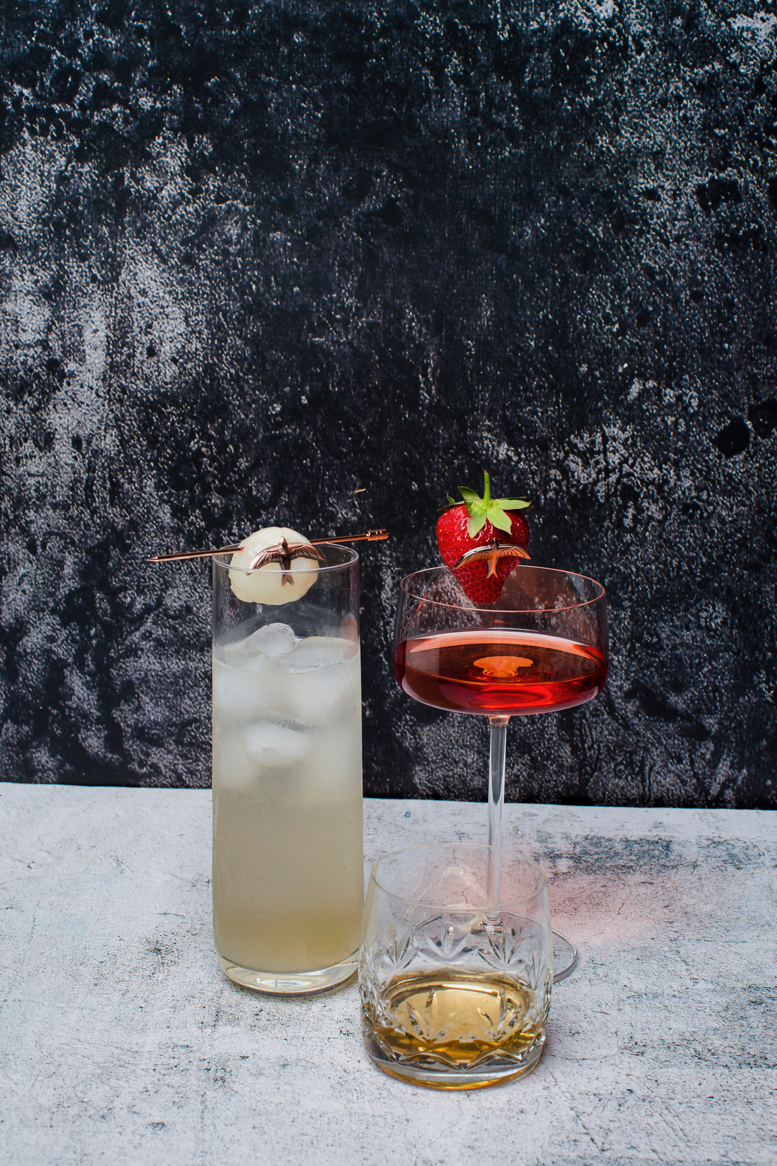 Three drinks next to each other, one in a tumbler, one in a tall glass and one in a martini glass