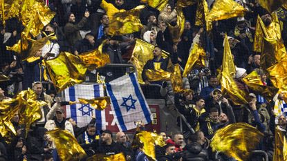 Maccabi supporters wave yellow flags next to Israeli flags during the UEFA Europa League football match between Ajax Amsterdam and Maccabi Tel Aviv at the Johan-Cruijff stadium, in Amsterdam on November 7, 2024