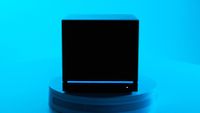 A Steam Machine in the dark, showing the blue LED light strip against the black chassis with a bright blue background