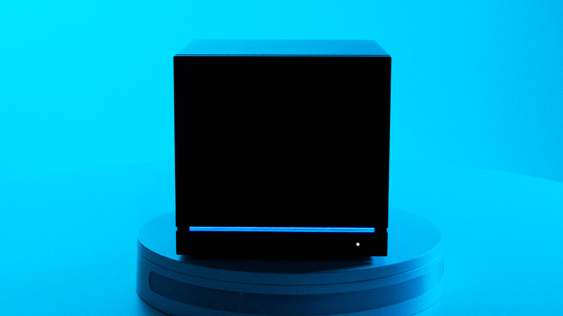 A Steam Machine in the dark, showing the blue LED light strip against the black chassis with a bright blue background