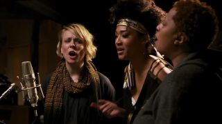 Three singers in front of a microphone in 20 Feet From Stardom