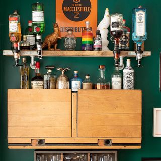 green wall with wooden shelf and bottles of alcohol