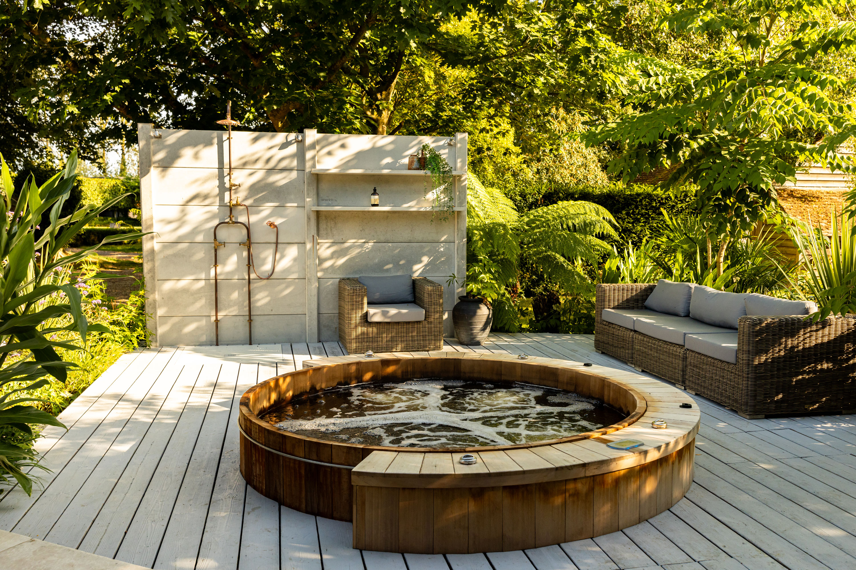hot tub, outdoor shower and decking with ferns and other planting