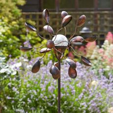 Gemini Wind Spinner with Solar Crackle Globe in a thriving garden during the day