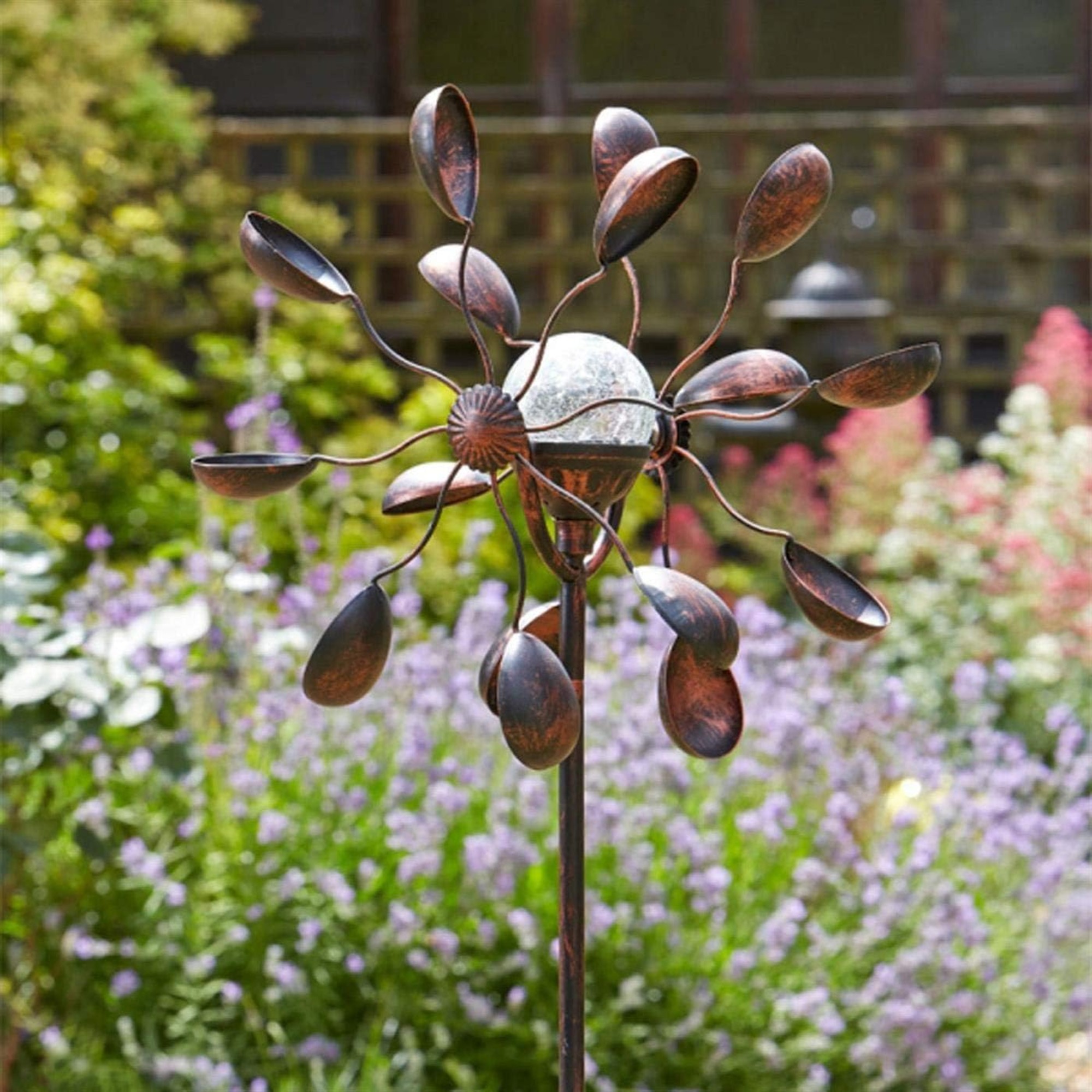 Gemini Wind Spinner with Solar Crackle Globe in a thriving garden during the day