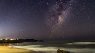 The Milky Way above a starlit beach.