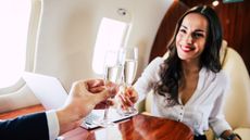 A wealthy woman and man toast with champagne on a private jet.