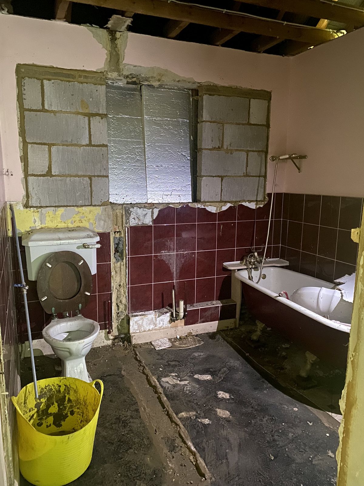 A bathroom being renovated with red tiles being removed