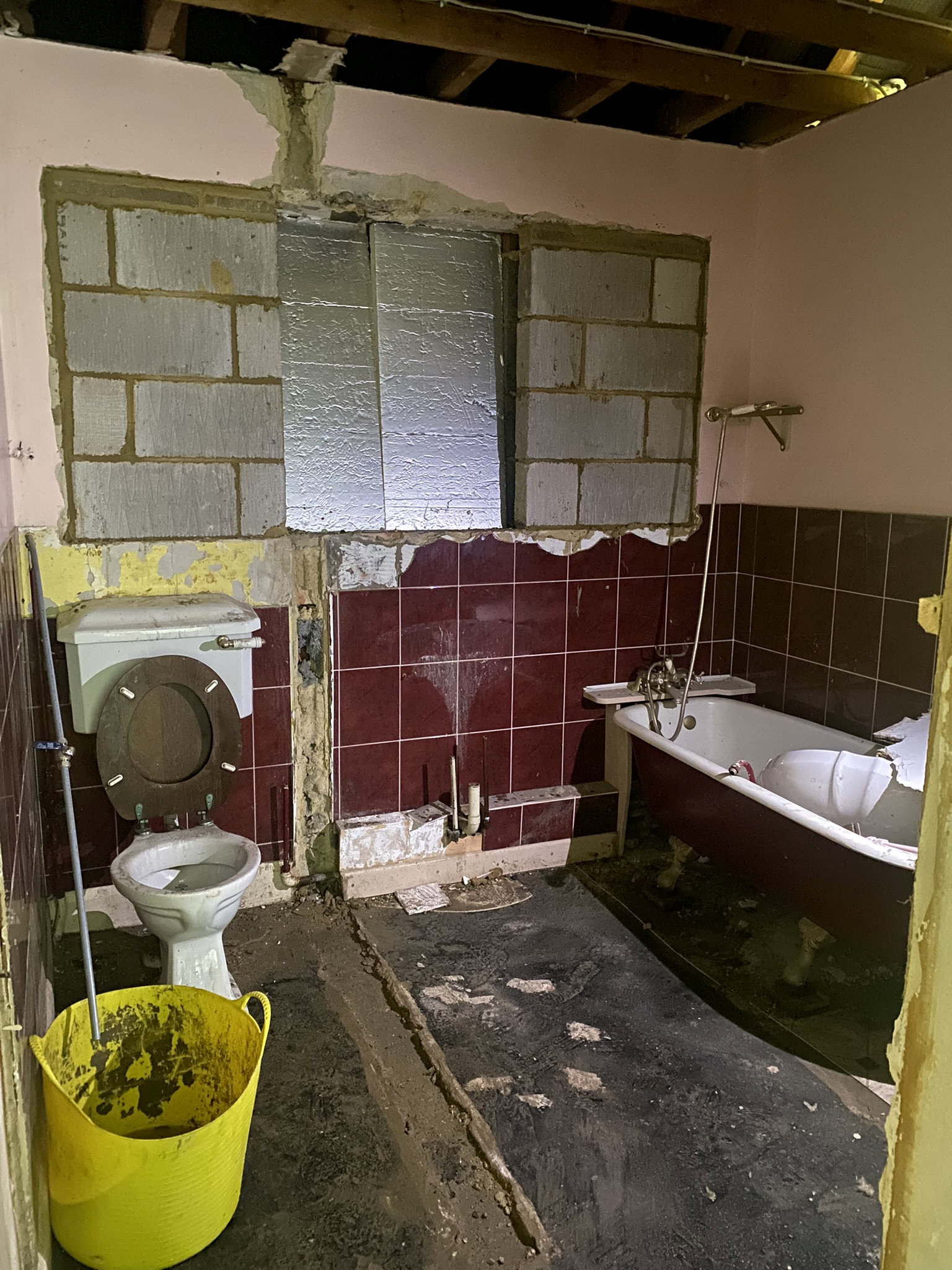 A bathroom being renovated with red tiles being removed