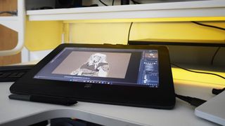 A photo of the XPPEN Artist Pro 14 (Gen 2) tablet on a white desk with a drawing on the screen