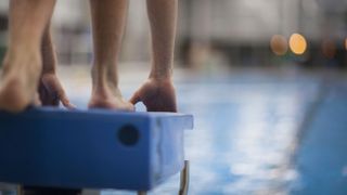 Swimmer's feet braced against diving board